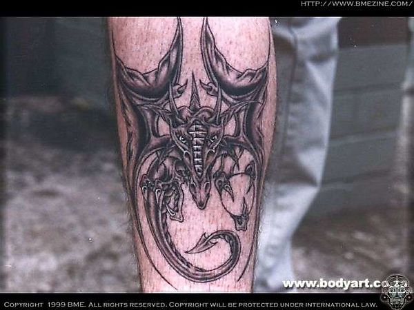 Татуировка жуткого дракона на мужской ноге
