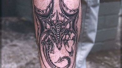 Татуировка жуткого дракона на мужской ноге